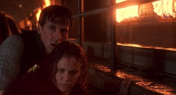 Movie still from “Daylight” (1996), directed by Rob Cohen – A man and a woman sitting next to each other in front of a fire; Close Up shot, Low angle