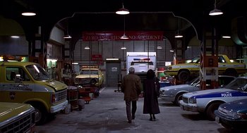 Movie still from “Daylight” (1996), directed by Rob Cohen – A man and a woman walking through a garage full of cars; Wide shot, High angle