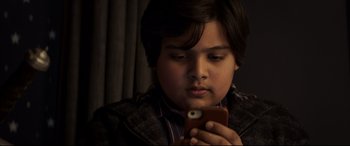 Movie still from “The Kid Who Would Be King” (2019), directed by Joe Cornish – A young boy looking at a cell phone; Close Up shot, High angle