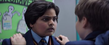 Movie still from “The Kid Who Would Be King” (2019), directed by Joe Cornish – A young boy in a suit and tie looking at the camera; Close Up shot, Over the shoulder angle