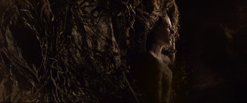 Movie still from “The Kid Who Would Be King” (2019), directed by Joe Cornish – A woman is standing in a cave with a lot of branches; Medium shot, Low angle