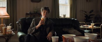 Movie still from “The Kid Who Would Be King” (2019), directed by Joe Cornish – A man sitting on a couch drinking a drink; Medium shot, Over the shoulder angle