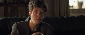 Movie still from “The Kid Who Would Be King” (2019), directed by Joe Cornish – A man sitting on top of a couch in a living room; Close Up shot, Over the shoulder angle