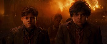 Movie still from “The Kid Who Would Be King” (2019), directed by Joe Cornish – Two men are standing in front of a fire; Close Up shot, Low angle