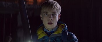 Movie still from “The Kid Who Would Be King” (2019), directed by Joe Cornish – A young man in a blue jacket is looking at the camera; Close Up shot, Low angle
