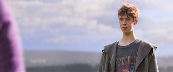 Movie still from “The Kid Who Would Be King” (2019), directed by Joe Cornish – A man standing in front of a mountain range; Medium shot, Low angle