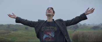 Movie still from “The Kid Who Would Be King” (2019), directed by Joe Cornish – A young man with his arms outstreched and his eyes closed; Medium shot, Low angle