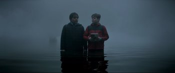 Movie still from “The Kid Who Would Be King” (2019), directed by Joe Cornish – Two young men standing in a body of water; Wide shot, Low angle