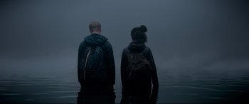 Movie still from “The Kid Who Would Be King” (2019), directed by Joe Cornish – Two people standing in the middle of a body of water; Medium shot, Over the shoulder angle