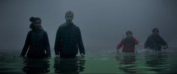 Movie still from “The Kid Who Would Be King” (2019), directed by Joe Cornish – A man standing in the water with a boat in the background; Wide shot, Low angle