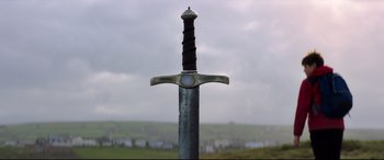 Movie still from “The Kid Who Would Be King” (2019), directed by Joe Cornish – A sword is shown in front of a cloudy sky; Close Up shot, Low angle