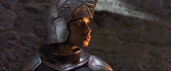 Movie still from “The Kid Who Would Be King” (2019), directed by Joe Cornish – A man wearing a metal helmet is looking to his left; Close Up shot, Over the shoulder angle
