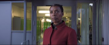Movie still from “The Kid Who Would Be King” (2019), directed by Joe Cornish – A woman wearing a red jacket standing in a hallway; Close Up shot, Over the shoulder angle