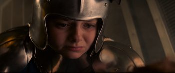 Movie still from “The Kid Who Would Be King” (2019), directed by Joe Cornish – A woman wearing a metal helmet looking at the camera; Close Up shot, High angle