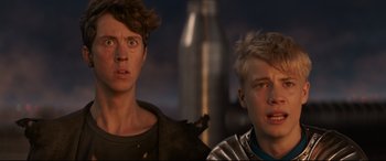 Movie still from “The Kid Who Would Be King” (2019), directed by Joe Cornish – Two young men standing next to each other in front of a bottle; Close Up shot, Low angle