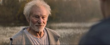 Movie still from “The Kid Who Would Be King” (2019), directed by Joe Cornish – An older man with white hair is smiling for the camera; Close Up shot, Over the shoulder angle