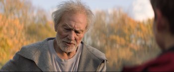 Movie still from “The Kid Who Would Be King” (2019), directed by Joe Cornish – An old man with a beard and a gray jacket; Close Up shot, Over the shoulder angle