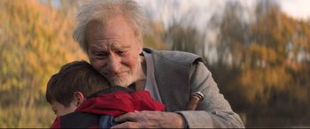 Movie still from “The Kid Who Would Be King” (2019), directed by Joe Cornish – An old man holding a young child in his arms; Close Up shot, Over the shoulder angle