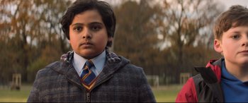 Movie still from “The Kid Who Would Be King” (2019), directed by Joe Cornish – A young boy wearing a suit and a tie; Medium shot, Low angle