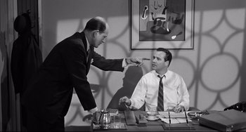 Movie still from “Days of Wine and Roses” (1962), directed by Blake Edwards – Two men in suits are sitting at a desk; Medium shot, Over the shoulder angle