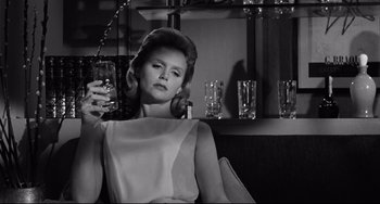Movie still from “Days of Wine and Roses” (1962), directed by Blake Edwards – A black and white photo of a woman holding a glass; Medium shot, Low angle