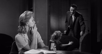 Movie still from “Days of Wine and Roses” (1962), directed by Blake Edwards – A woman smoking a cigarette in front of a man and a child; Medium shot, Low angle