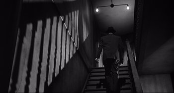 Movie still from “Days of Wine and Roses” (1962), directed by Blake Edwards – A man in a suit walking up a flight of stairs; Wide shot, Low angle