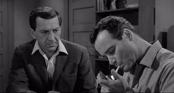 Movie still from “Days of Wine and Roses” (1962), directed by Blake Edwards – A man smoking a cigarette while another man looks on; Close Up shot, High angle