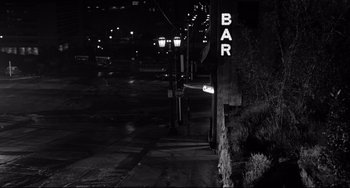 Movie still from “Days of Wine and Roses” (1962), directed by Blake Edwards – A black and white photo of a street corner at night; Extreme Wide shot, High angle