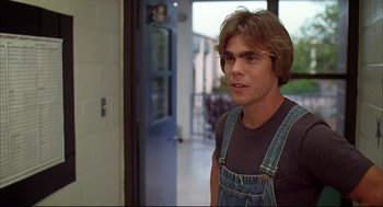 Movie still from “Dazed and Confused” (1993), directed by Richard Linklater – A young man wearing overalls standing next to a door; Close Up shot, Over the shoulder angle