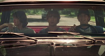 Movie still from “Dazed and Confused” (1993), directed by Richard Linklater – Three young men are sitting in the back seat of a car; Medium shot, Low angle