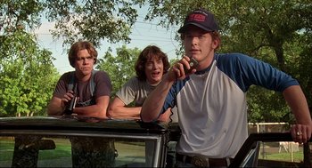Movie still from “Dazed and Confused” (1993), directed by Richard Linklater – A group of young men standing next to each other on top of a car; Medium shot, Low angle