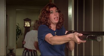 Movie still from “Dazed and Confused” (1993), directed by Richard Linklater – A woman with red curly hair holding a wii controller; Medium shot, Over the shoulder angle