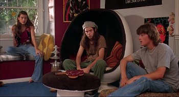 Movie still from “Dazed and Confused” (1993), directed by Richard Linklater – A man sitting in a chair in a living room; Medium shot, High angle