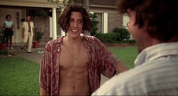 Movie still from “Dazed and Confused” (1993), directed by Richard Linklater – A man that is smiling for the camera; Medium shot, Low angle