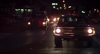 Movie still from “Dazed and Confused” (1993), directed by Richard Linklater – Cars are driving down a street at night; Wide shot, Low angle