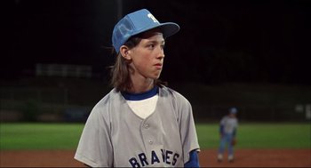 Movie still from “Dazed and Confused” (1993), directed by Richard Linklater – A young baseball player wearing a blue hat; Medium shot, Over the shoulder angle