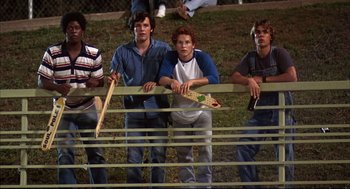 Movie still from “Dazed and Confused” (1993), directed by Richard Linklater – A group of young men standing next to each other on a field; Medium shot, Low angle