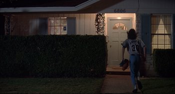Movie still from “Dazed and Confused” (1993), directed by Richard Linklater – A person is walking out of a house at night; Wide shot, Low angle