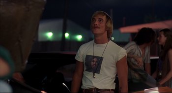 Movie still from “Dazed and Confused” (1993), directed by Richard Linklater – A man with a mustache wearing a t - shirt with a picture of a man on it; Close Up shot, Low angle