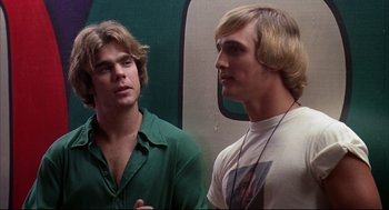 Movie still from “Dazed and Confused” (1993), directed by Richard Linklater – Two young men standing next to each other in front of a wall; Close Up shot, Over the shoulder angle