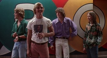 Movie still from “Dazed and Confused” (1993), directed by Richard Linklater – Two young men standing next to each other in front of a mural; Medium shot, Low angle