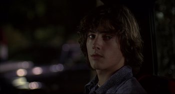 Movie still from “Dazed and Confused” (1993), directed by Richard Linklater – A young man with long brown hair stares into the camera; Close Up shot, Over the shoulder angle