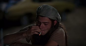 Movie still from “Dazed and Confused” (1993), directed by Richard Linklater – A man with a hat is smoking a cigarette; Medium shot, Low angle