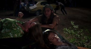Movie still from “Dazed and Confused” (1993), directed by Richard Linklater – A group of young people laying on top of a field; Medium shot, High angle