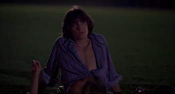 Movie still from “Dazed and Confused” (1993), directed by Richard Linklater – A man sitting in the grass at night; Medium shot, Over the shoulder angle