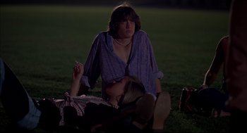 Movie still from “Dazed and Confused” (1993), directed by Richard Linklater – A man sitting on the grass with a cigarette in his mouth; Medium shot, Low angle