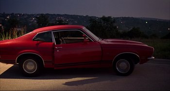 Movie still from “Dazed and Confused” (1993), directed by Richard Linklater – A red sports car driving down a street at night; Wide shot, High angle