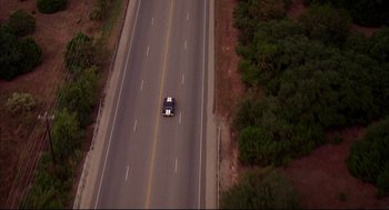 Movie still from “Dazed and Confused” (1993), directed by Richard Linklater – An aerial view of a car driving down the road; Extreme Wide shot, Overhead angle
