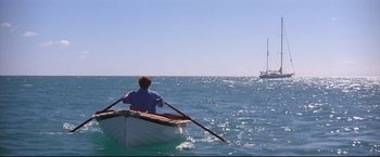 Movie still from “Dead Calm” (1989), directed by Phillip Noyce – A man rowing a boat in the middle of the ocean; Extreme Wide shot, High angle